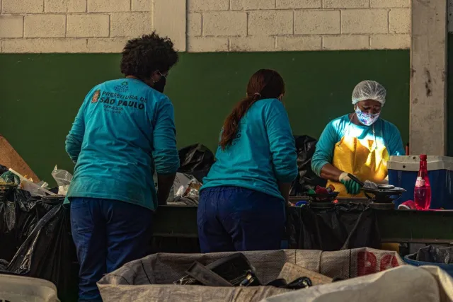 Trabalhadoras da limpeza urbana da Prefeitura de São Paulo fazem a triagem de resíduos em uma central, entre sacos de lixo e materiais descartados, em meio ao debate sobre o incinerador de lixo em Perus, discussão sobre quantidade de reciclagem na cidade é reacendida.